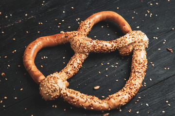 Fresh prepared homemade soft pretzels. Different types of baked pretzels with seeds on a black background