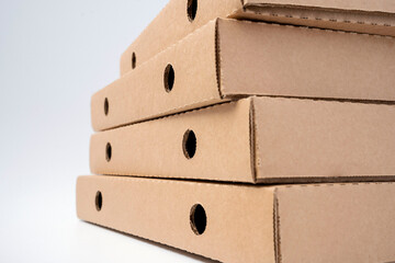 Stack flat brown cardboard pizza boxes on a white background