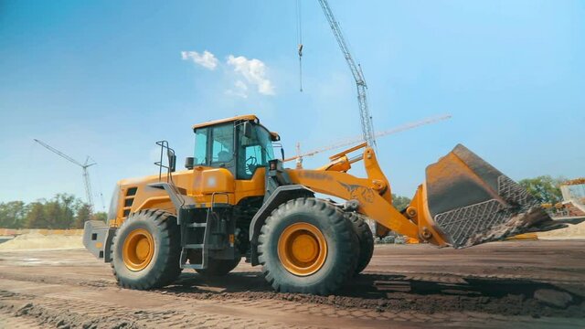 Modern tractor on a construction site. Large yellow tractor. Professional construction equipment. Work process at a construction site