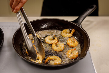 Fried shrimp on pan, preparing dish with seafood.