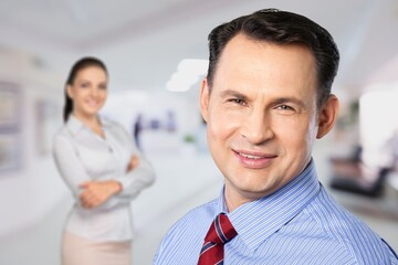 A couple of smiling business people on the office background