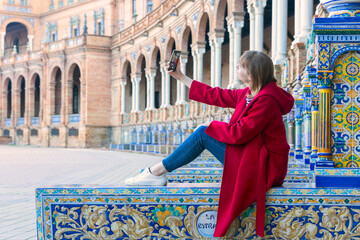 blonde woman tourist taking a selfie in the plaza de españa in seville