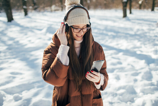 Young woman listening music with headphones on winter day