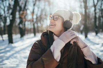 Young woman enjoy winter day and listening music with headphones 