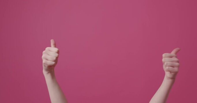 Woman points thumb up against an isolated pink background.Approval hand gestures