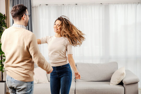 A happy couple dancing and having fun at their new cozy apartment.