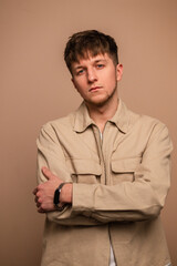 Obraz premium Stylish cool man model with hair in fashionable clothes on a beige background
