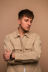 Fototapeta premium Cool young stylish man with a hairstyle in fashionable outerwear on a beige background