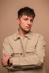 Obraz premium Handsome man in fashionable outerwear with stylish beige jacket and white t-shirt posing on a beige background and looking at the camera