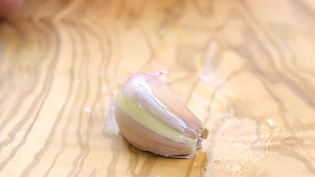 Slow motion of hand placing a garlic clove in cutting board