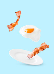 Bacon and egg as English breakfast levitate over a plate on a blue background