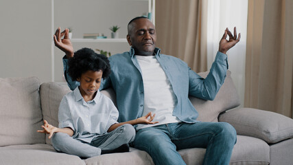 African american father and child sitting on sofa with closed eyes mature dad teaches little daughter to meditate manage emotion calm down do yoga relaxing kid girl sits in lotus position meditation - obrazy, fototapety, plakaty