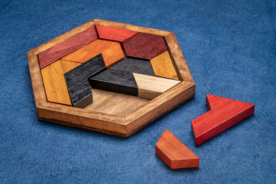 wooden hexagon tangram puzzle against textured handmade bark paper, brain teaser and fun game with multiple ways to solve