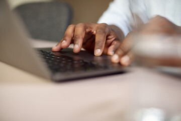 Close-up of black businessman types e-mail while working on computer in the office.
