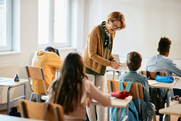 Mature teacher assists her student on a class at elementary school.