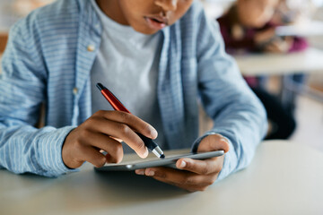 Close-up of black schoolboy uses touchpad during computer class in the classroom.