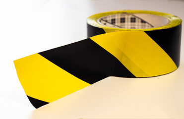 A roll of enclosing yellow tape with black stripes on a white isolate.