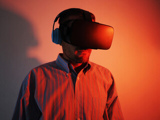 Man wearing a VR headset and wireless headphones,  futuristic red neon light.