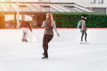 Soft,Selective focus.People, friendship, sport and leisure concept - happy friends on skating rink.Group of teenage friends ice skating on an ice rink. © Nataliia