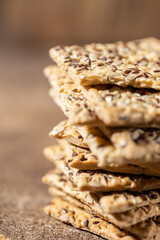 Stack of biscuit crackers with sunflowers seeds and sesame, vertical selective focus