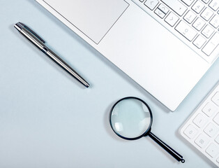 Business research and information technology concept. Laptop, magnifier, pen and calculator.