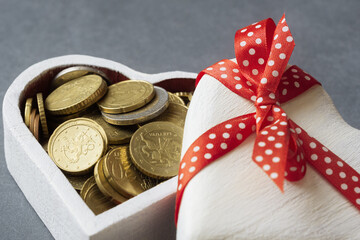 Close up of Euro coins in heart shaped gift box on grey stone background. Love and money concept