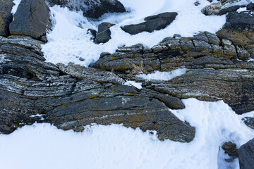 Granite layered rocks covered with snow in the arctic, Close up view from above