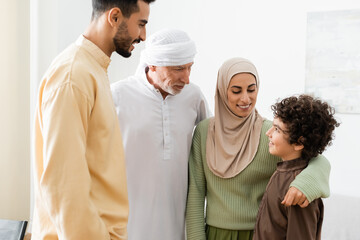 smiling muslim woman hugging arabian son near father and husband.