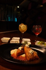 Fish with vegetables on plate and cocktails in the background.