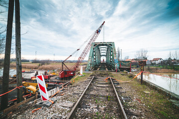 Fototapeta na wymiar Disassembly and cutting of the old steel railway bridge and rusty rails