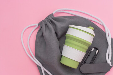 Trendy environmental friendly reusable cup. Reusable silicone ear stick. Grey shopping mesh bag. Concept of conscious consumption. Alternatives to disposables.
