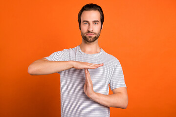 Photo of young man show hands time-out symbol referee rejection isolated over orange color...