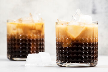 White russian cocktail, trendy alcoholic drink with vodka, coffee liqueur, cream and ice, gray background, bar tools, copy space