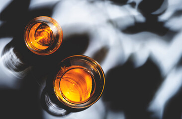 Strong drinks in glasses: cognac, whiskey. White background with hard light and harsh shadows