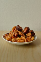 Close up of white porcelain plate full of crispy salty pork greaves on wooden desk with white background