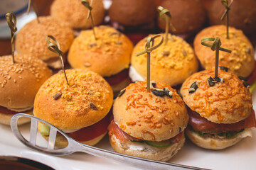 Burger mini burgers snacks on a wooden table with craft paper, beautifully decorated catering banquet table on corporate christmas birthday party event or wedding celebration