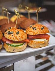 Burger mini burgers snacks on a wooden table with craft paper, beautifully decorated catering banquet table on corporate christmas birthday party event or wedding celebration