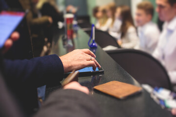 Process of checking in on a conference congress forum event, registration desk table, visitors and attendees receiving a name badge and entrance wristband bracelet and register electronic ticket,