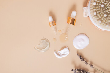 Smears and drops of various cosmetic products top view and pipettes on beige background with dry...
