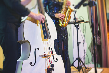 Concert view of contrabass violoncello player with vocalist and music band during jazz orchestra...