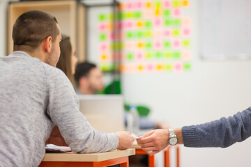 Students secretly passing sheets of paper during exam in a modern classroom.