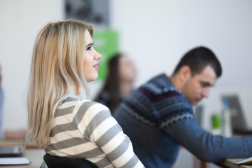 Young student in modern classroom listening to lecture.