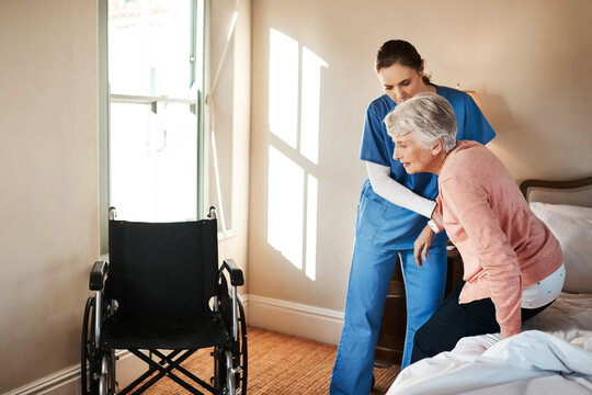 Simple movements aren't so simple anymore. Shot of a young nurse helping a senior woman get up from her bed in a nursing home.