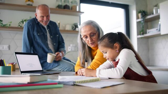 Small girl with senior grandparents doing maths homework at home.