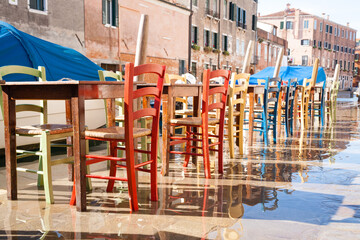 Fototapeta na wymiar Colorful chairs in a row along Venetian canal