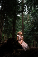 Young girl in pink dress in the forest 