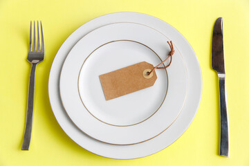 Serving two plates, spoon, fork, knife on the yellow background. The concept of weight loss and diet. The concept of weight loss and diet. Label with the inscription - diet in an empty plate