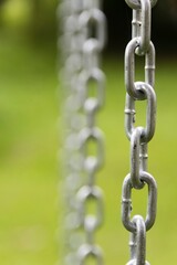 Iron chain extended vertically. Selective focus and green background.