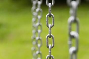 Iron chain extended vertically. Selective focus and green background.