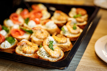 Bruschetta with shrimps on a black tray.